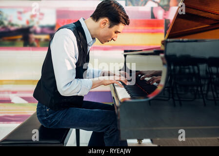 Male pianist practicing composition on grand piano Stock Photo