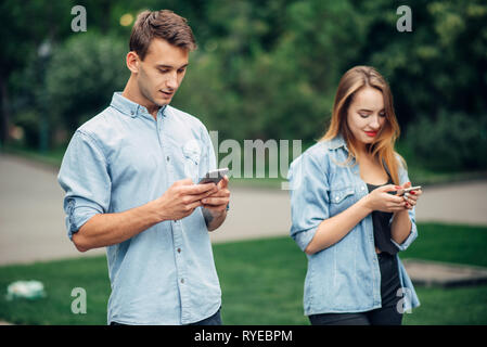 Phone addicted people, couple in summer park Stock Photo