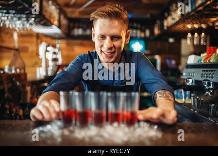 Male bartender prepares four beverages in glasses Stock Photo