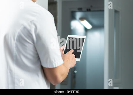 Bright close up of male doctor in uniform with stethoscope and using computer tablet in hospital. Modern medical concept Stock Photo