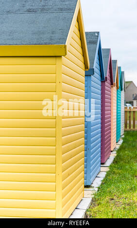 Amble, Northumberland, UK - February 2017: Colourful huts (yellow, blue, pink, green) located close to the beach Stock Photo