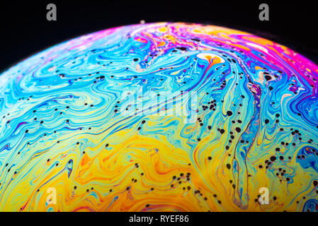 Abstract background made from soap bubble reflecting light. Rainbow soap bubble on a dark background. Stock Photo