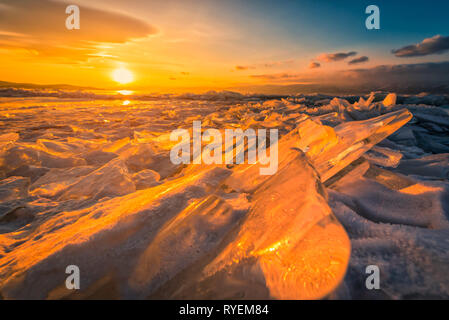 Sunset sky with natural breaking ice over frozen water on Lake Baikal, Siberia, Russia. Stock Photo