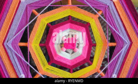 A colorful knitted web using the yarns with different colors using sticks to make the design Stock Photo