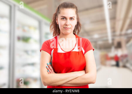 Portrait of female supermarket or hypermarket employee with crossed arms and serious expression Stock Photo