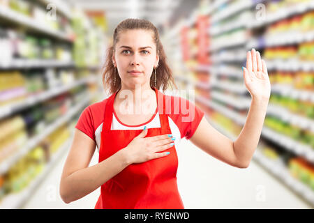 Female hypermarket or supermarket employee making honest oath with hand on heart and palm up Stock Photo