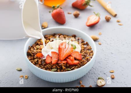 Granola with pouring milk, banana and strawberries. Healthy breakfast. Stock Photo