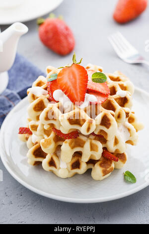 Belgium waffles topped with cream and fresh strawberries for dessert. Stock Photo