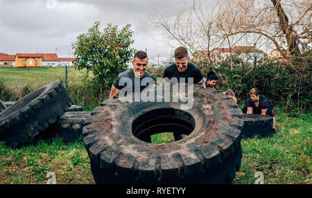 Participants in an obstacle course turning a wheel Stock Photo