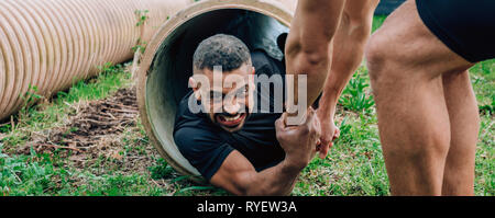 Participants obstacle course going through a pipe Stock Photo