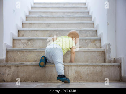 Baby girl crawling up stairs outdoors, rear view Stock Photo
