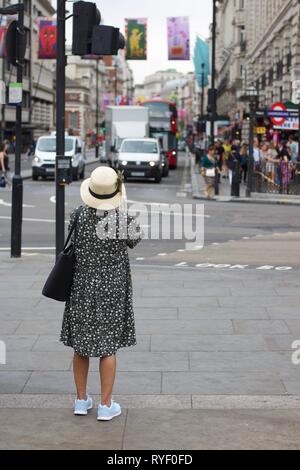 London tourist in dress and hat looking down Piccadilly Stock Photo