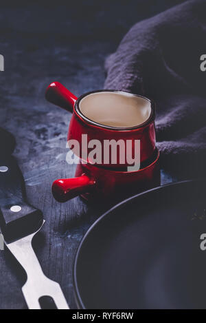 Vertical photo with two cups. Cups or small bowls have saturated red color, black edge and white inner side. Cups are stacked and placed on dark woode Stock Photo