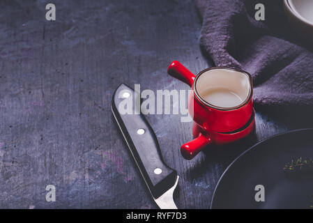 Horizontal photo with two cups. Cups or small bowls have saturated red color, black edge and white inner side. Cups are stacked and placed on dark woo Stock Photo