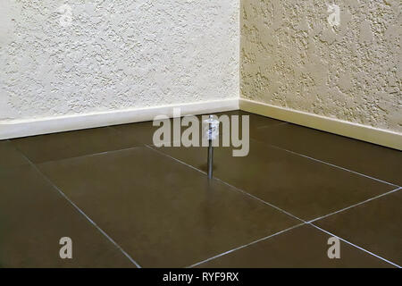 Door stop, located in the corner of the room, on the floor of a tile of brown color. Stock Photo
