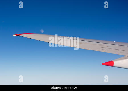 Aircraft wing with moon and blue sky taken from aircraft window