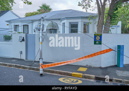 Fallen pole and wires unto a fence wall and house on street corner in southern suburbs of Cape Town, South Africa Stock Photo