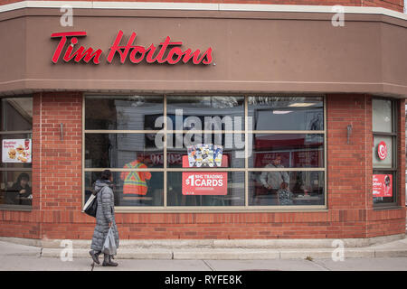 OTTAWA, CANADA - NOVEMBER 12, 2018: Tim Hortons logo in front of one of their restaurants in Ottawa, Ontario, with pedestrians oassing by. Tim Hortons Stock Photo