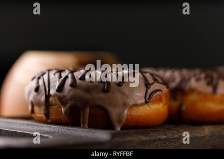 Cookery, baking and food concept - closeup. Two donuts in the glaze on the decorative board. Appetizing still life. Stock Photo