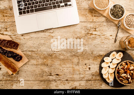 Wooden table set for a sweet vegan breakfast shot from above with sliced banana, mixed dried fruit, vegan biscuits, slices of bread with jam and veg h Stock Photo