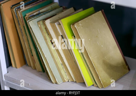 Many different books are on the open shelf at a wall Stock Photo