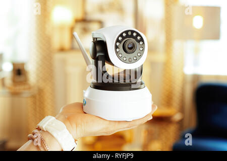 Closeup on wifi security camera in hand of modern woman in the living room. Stock Photo