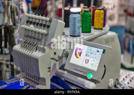 professional machine for applying embroidery on different tissues with colorful reels of threads closeup Stock Photo