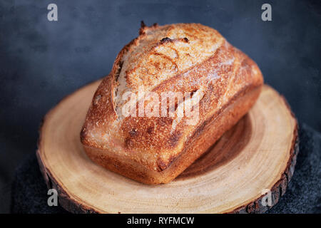 rectangle loaf of freshly baked homemade artisan sourdough bread on a round wood plank - image Stock Photo