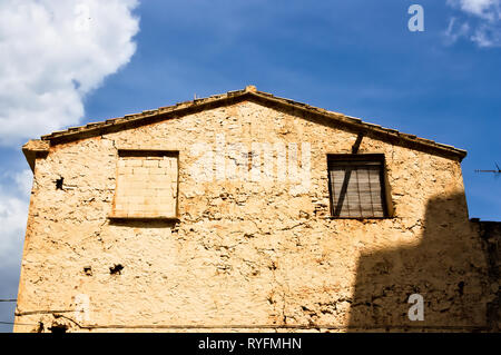 Facade of an old house with two windows aged by time and neglect Stock Photo