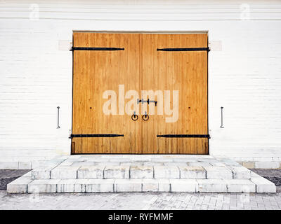 White brick wall with wooden door bolt, handles and hinges made of wrought iron. Medieval architecture Stock Photo