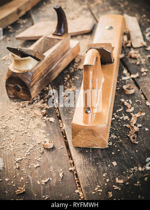 Old woodworking hand tool: wooden plane, chisel and in a carpentry workshop on dirty rustic table covered with sawdust background side view Stock Photo