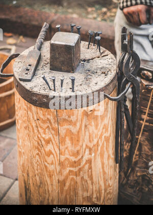 Metalworking tools of blacksmith. The hammer and the anvil and other tools outdoor green grass background. Stock Photo