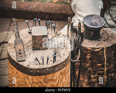 Metalworking tools of blacksmith. The hammer and the anvil and other tools outdoor green grass background. Stock Photo