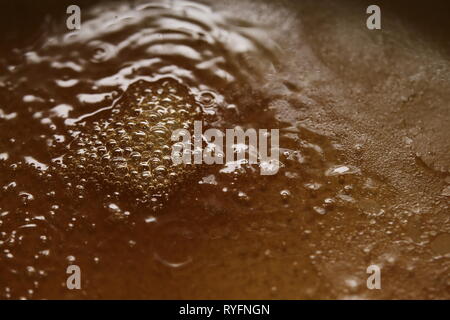 Boiling viscous liquid with orange color and bubbles. Stock Photo