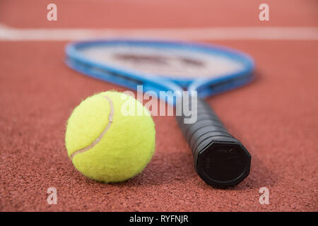 Tennis ball and racket on the hard court Stock Photo