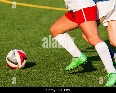 Two girls chasing a soccer ball during a high school game on a sunny afternoon. Stock Photo