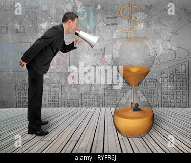 Businessman using megaphone yelling at man flooded in hourglass with doodles wall and wooden floor background Stock Photo