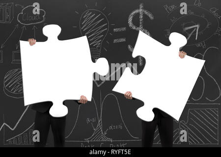 Two business people assembling blank white jigsaw puzzles on business concept doodles background Stock Photo