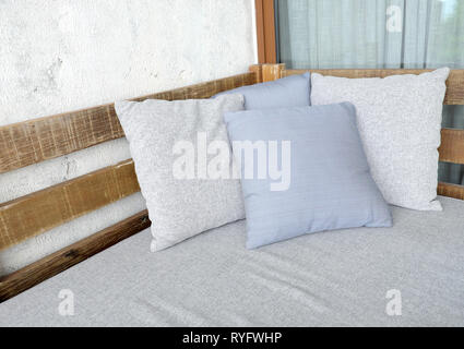 Close up of a wood sofa with styled cushions and throw Stock Photo