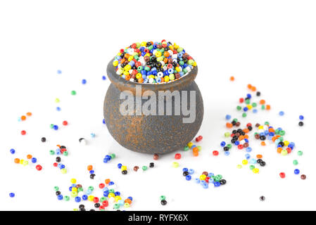 Heap of multi-colored beads for needlework in a small ceramic pot isolated on a white background Stock Photo