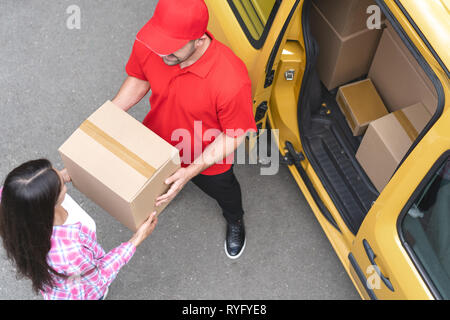 Courier is giving delivery parcel to young woman. Top view Stock Photo