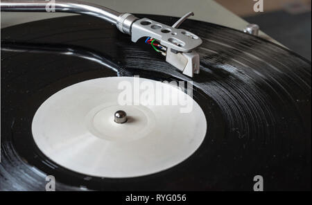 Closeup turntable player playing vinyl record disc. Focus on needle cartridge headshell. Hifi sound system Stock Photo