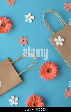 Coral gerbera daisy flowers and craft papper shopping bags on green paper background, Springtime sale concept image with copy-space Stock Photo