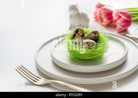 Easter table setting with pink tulip on white. Spring romantic dinner. Space for your text. Stock Photo