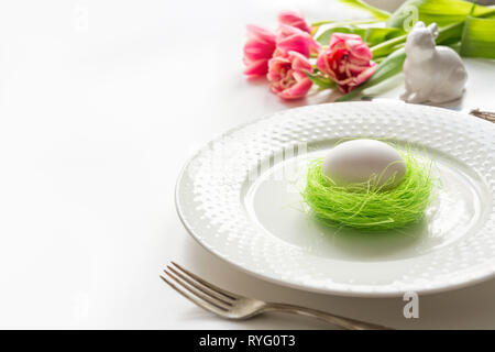 Easter table setting with pink tulip on white. Spring romantic dinner. Space for your text. Stock Photo