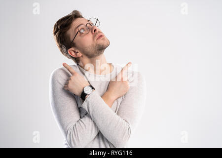Young emotional careless man isolated on white background with copy space for text put his head on his fist and look aside stand in casual outfit Stock Photo