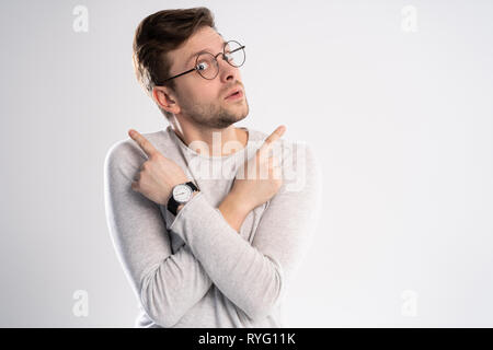 Young emotional careless man isolated on white background with copy space for text put his head on his fist and look aside stand in casual outfit Stock Photo