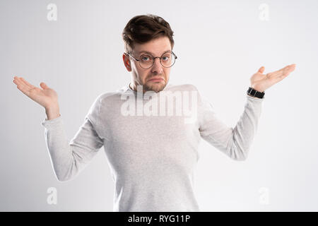 Young emotional careless man isolated on white background with copy space for text put his head on his fist and look aside stand in casual outfit Stock Photo