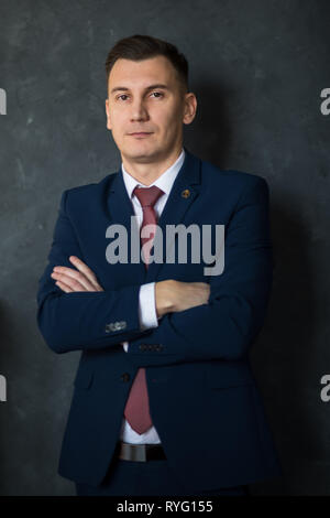 Portrait of young intelligent man lawyer standing with crossed arms in modern office building interior, successful male bank employee dressed in Stock Photo