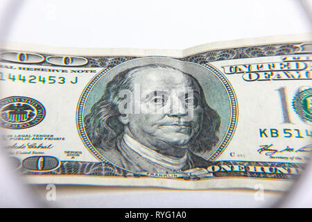 Dollar banknotes under magnifying glass. The concept of business: hundred-dollar bills are considered under a magnifying glass. Hundred dollar bill un Stock Photo